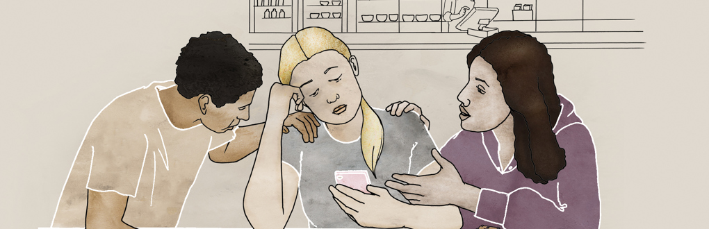 En tjej med mobiltelefon får stöd av två kompisar
