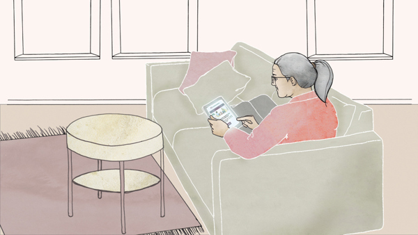 Kvinna som sitter i soffan och läser på en ipad. 