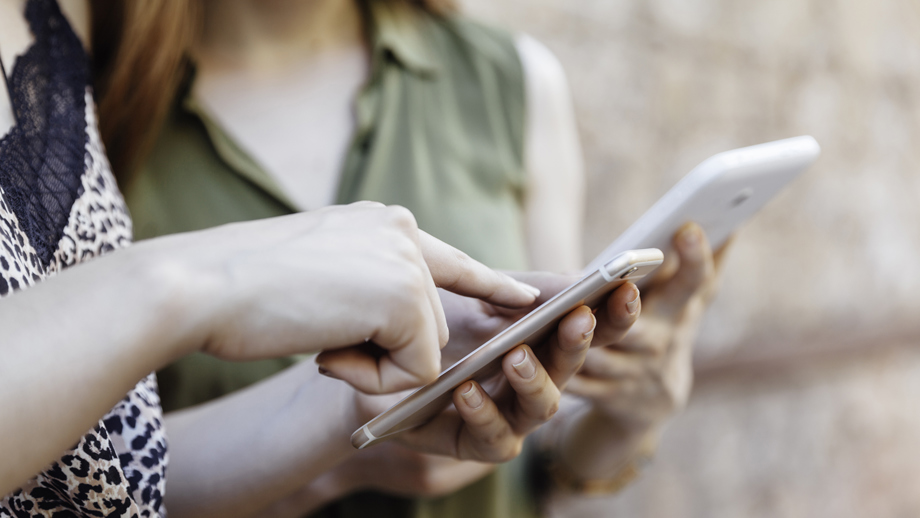 Två personer som håller i mobiler och pekar på skärmarna. Foto: cometary/iStock