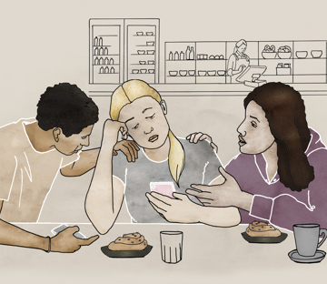 En tjej med mobiltelefon får stöd av två kompisar.