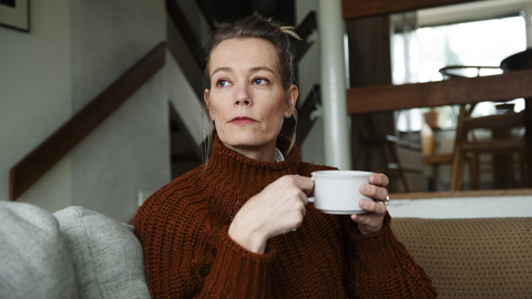 Person som sitter i en soffa och håller i en kopp.