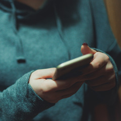 Ung person i blå hoodie som tittar i mobil. Foto: Lajst/Getty Images