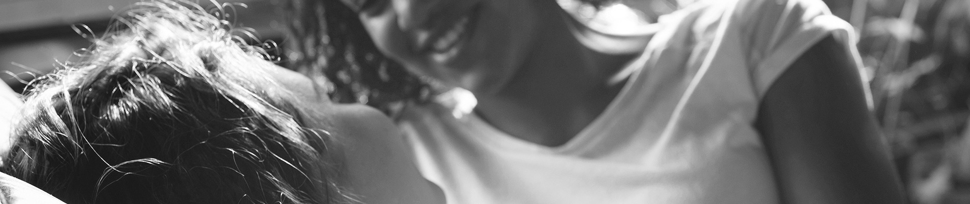 Svartvit bild på en vuxen som pratar med ett barn som ligger i sängen